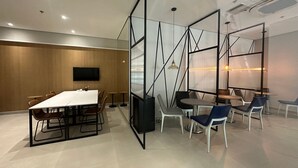 A modern meeting room with a long table, chairs, a TV, and glass partitions. - TrevizZo Borba Gato (São Paulo)
