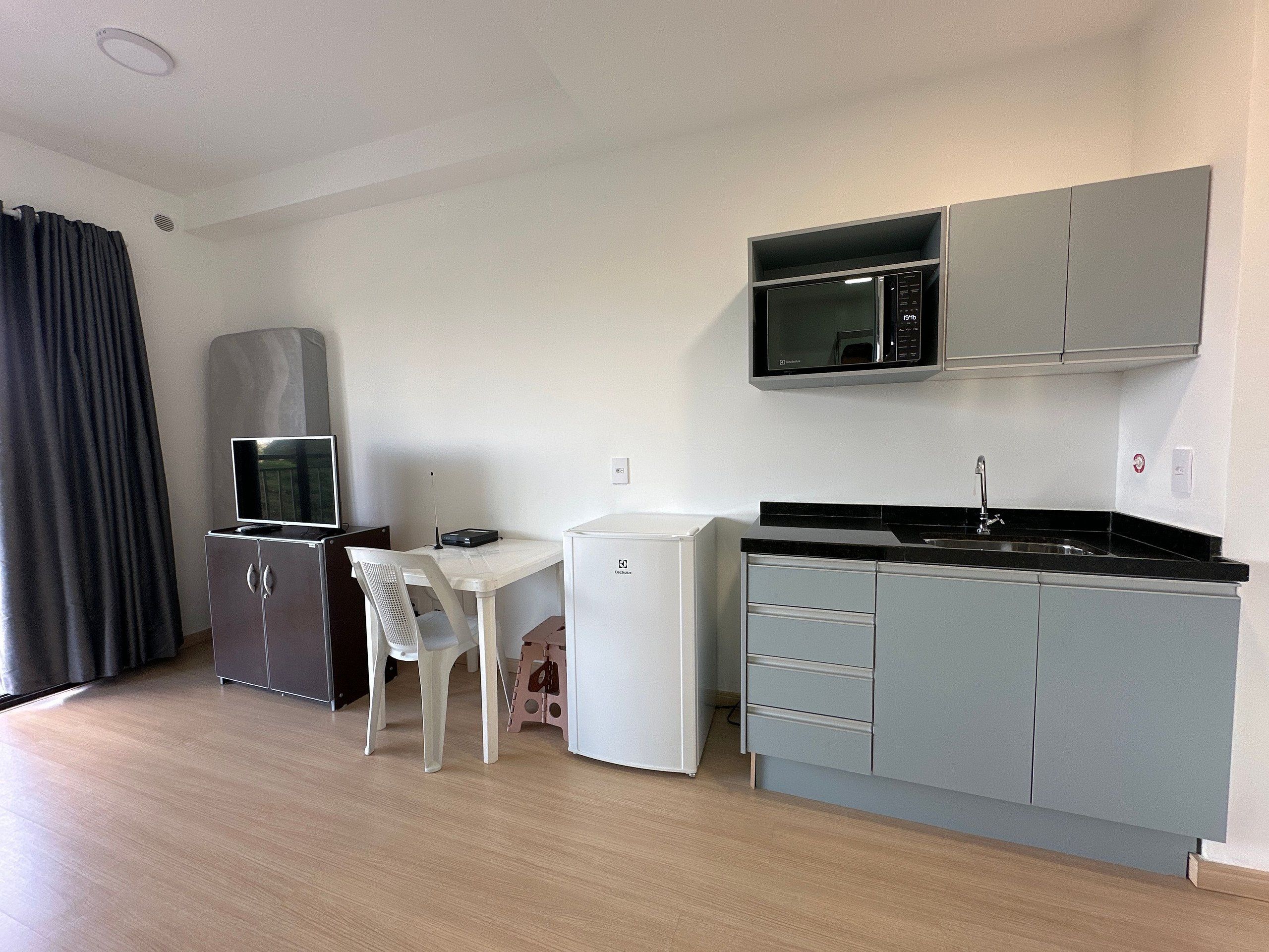 A compact kitchen with a microwave, refrigerator, and a small dining area.