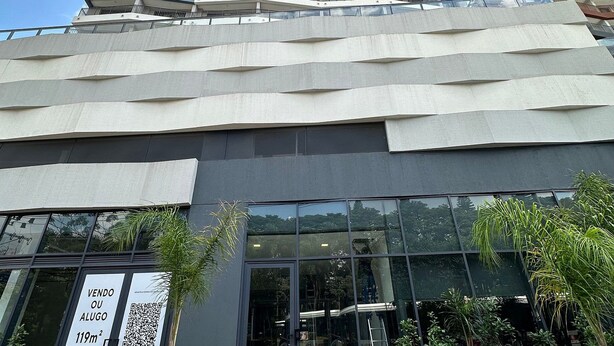 A modern building with a glass entrance, a sign indicating a sale, and a number 599 sign. - TrevizZo Borba Gato (São Paulo)