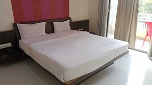 Un letto grande con testiera in legno, biancheria da letto bianca e una presa di corrente sul lato sinistro.