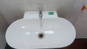 Un lavabo bianco con un solo rubinetto e scarico.