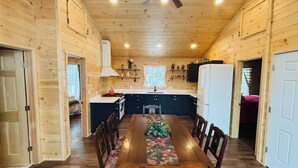 A wooden cabin interior with a dining table, chairs, a kitchen area, and a ceiling fan. - Charming 2-bedroom apartment in marvelous Bethlehem with WiFi (Bethlehem)