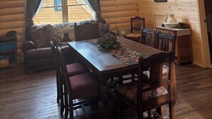 A cozy log cabin interior with a dining area, wooden ceiling, and a large window overlooking a house. - Charming 2-bedroom apartment in marvelous Bethlehem with WiFi (Bethlehem)
