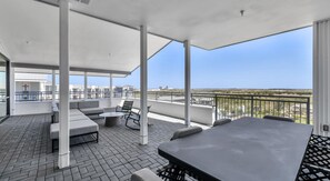 A covered outdoor patio with a view of the city skyline, featuring a dining table and seating area. - Landing | Stunning 1BD, Gym, Clubhouse (Kyle)