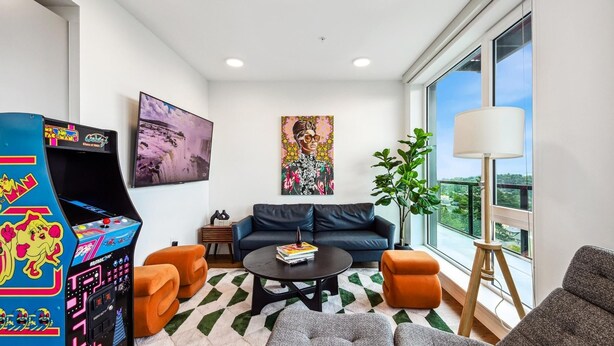 Ein modernes Wohnzimmer mit einer Couch, Sesseln, einem Couchtisch und einem großen Fenster mit Blick auf die Stadt.