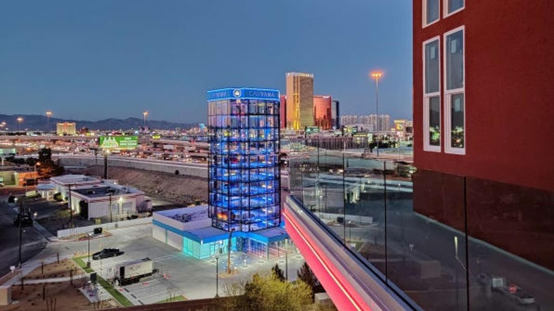 Een modern gebouw met een glazen gevel en een blauw verlichte ingang.