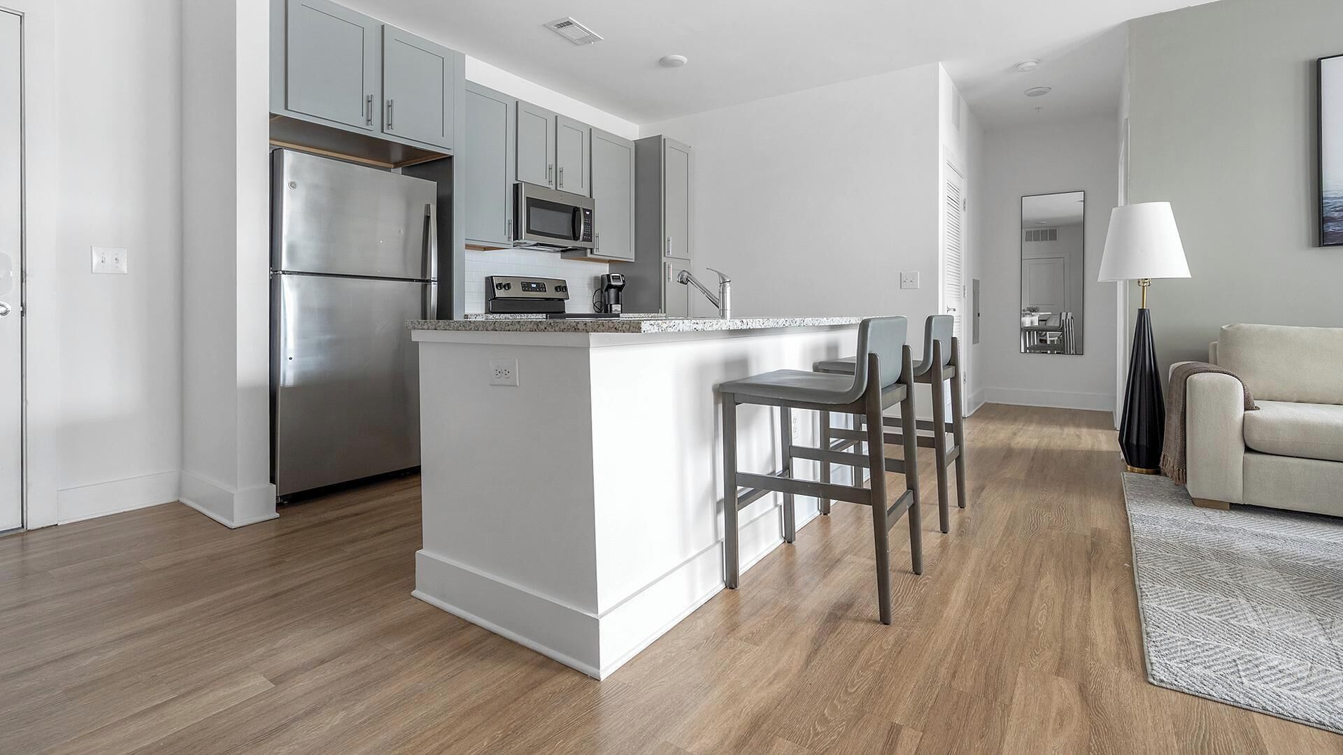 Una cocina moderna con electrodomésticos de acero inoxidable, una isla central con taburetes y un diseño minimalista.