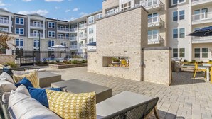 A courtyard with outdoor seating, a fire pit, and a pool in the background.