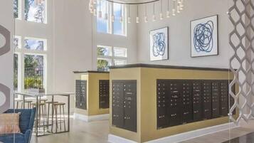 Un hall d’hôtel spacieux, doté d’un comptoir d’accueil central, d’un éclairage moderne suspendu et de grandes fenêtres laissant entrer la lumière naturelle.