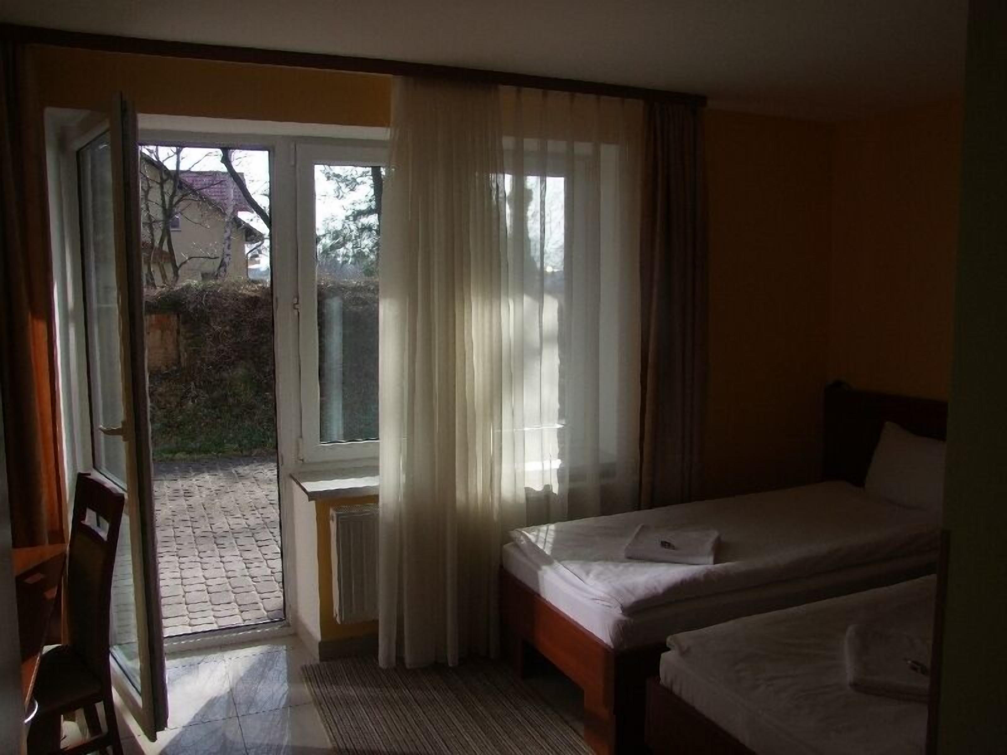 Habitación de hotel con cama doble, un escritorio pequeño y una puerta corrediza de vidrio que da a un espacio exterior.