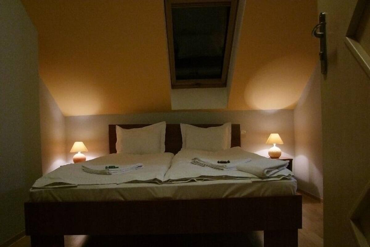 A bedroom with a bed, two bedside lamps, a window, and a door.