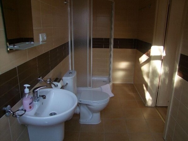 Un baño con lavamanos, inodoro y ducha.