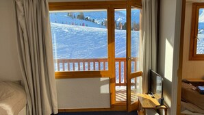 A room with a large window overlooking a snowy mountain landscape. - Studio with balcony in Plagne Village (Plagne Village)