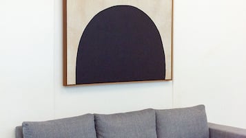 Una sala de estar moderna con un sofá gris, un cuadro abstracto grande y un tapete estampado.