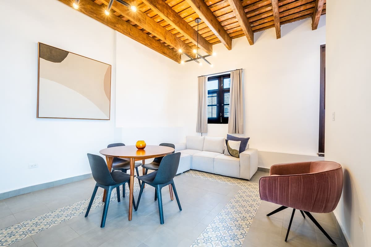A modern interior with a round table, four chairs, a sofa, and a red armchair.