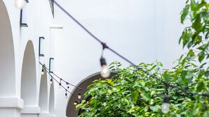 Un sendero estrecho que conduce a la entrada de un edificio, bordeado por paredes blancas y vegetación.