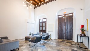 Un vestíbulo amplio con piso a cuadros, un sofá gris, una silla negra y una mesa de centro de madera.