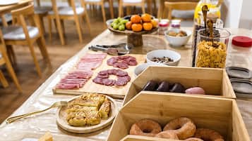 Una mesa de buffet con diversos alimentos, incluyendo carnes, pasteles y frutas.