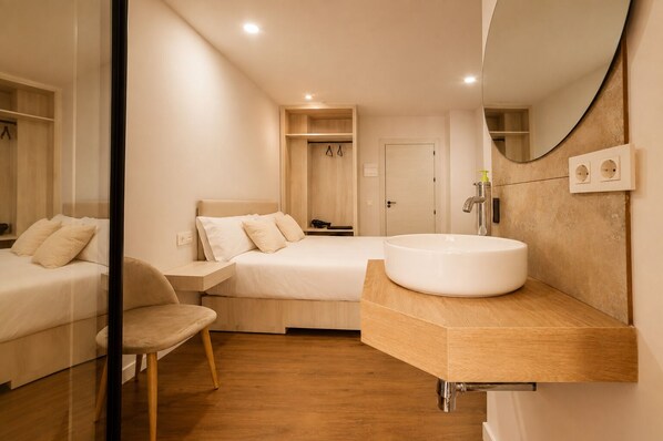 A modern bedroom with a large bed, a bedside table, a chair, a round white sink, and a mirror. - Casa Jazmin by Blossom Hotels (Granada)