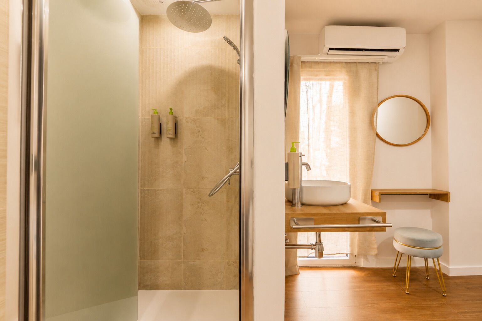 Un baño moderno con cabina de ducha de vidrio, un lavamanos con espejo y un equipo de aire acondicionado.