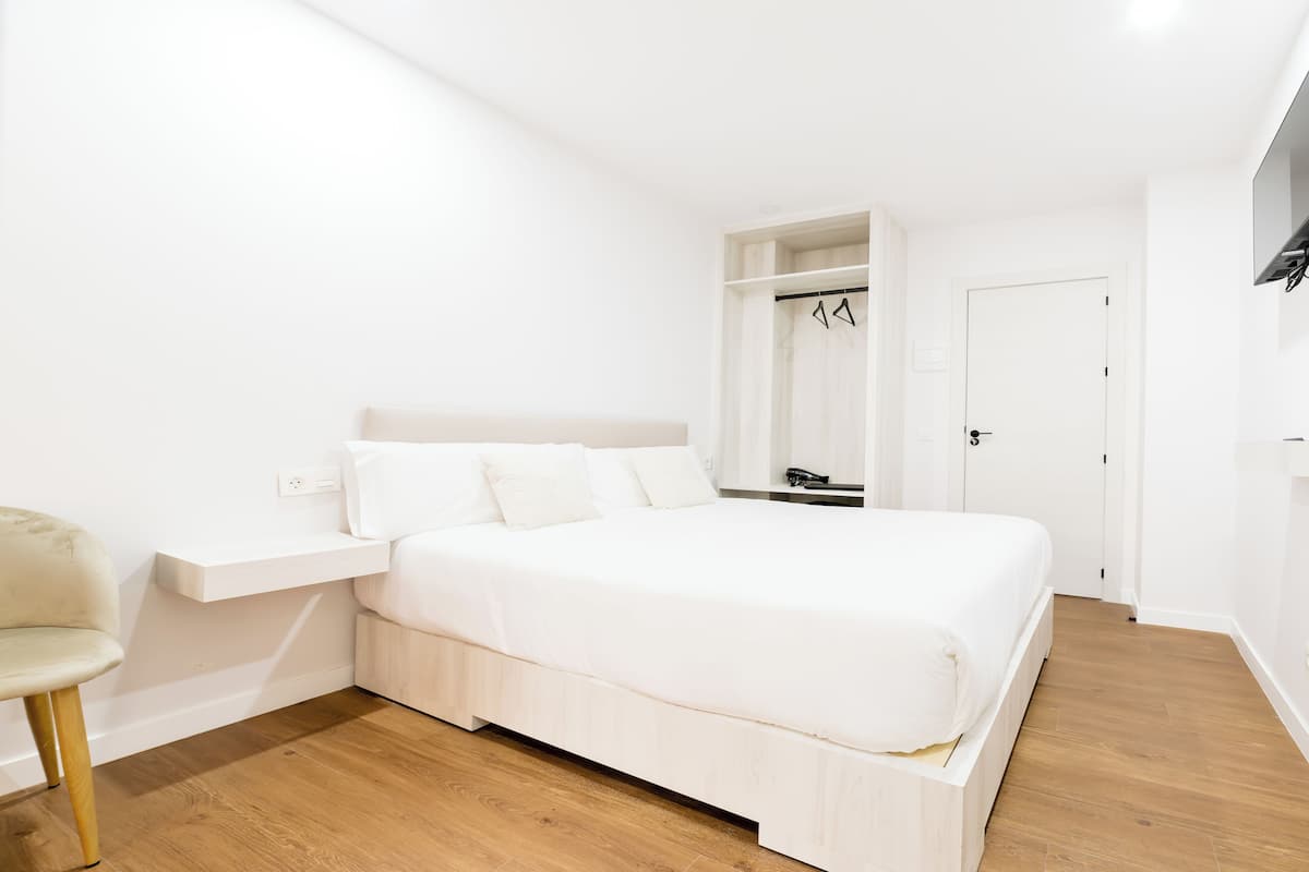 A modern bedroom with a large bed, a built-in wardrobe, and a bedside table.