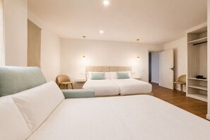 A modern bedroom with a large bed, bedside tables, a wardrobe, and a chair. - Casa Jazmin by Blossom Hotels (Granada)