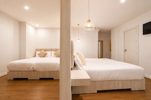 Un dormitorio con dos camas, piso de madera, una lámpara en el techo y una puerta.