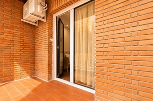 Habitación con paredes de ladrillo y un cristalero corredero que da a un espacio interior.