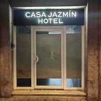 La entrada del Hotel Casa Jazmín, con puerta de cristal y un cartel arriba.