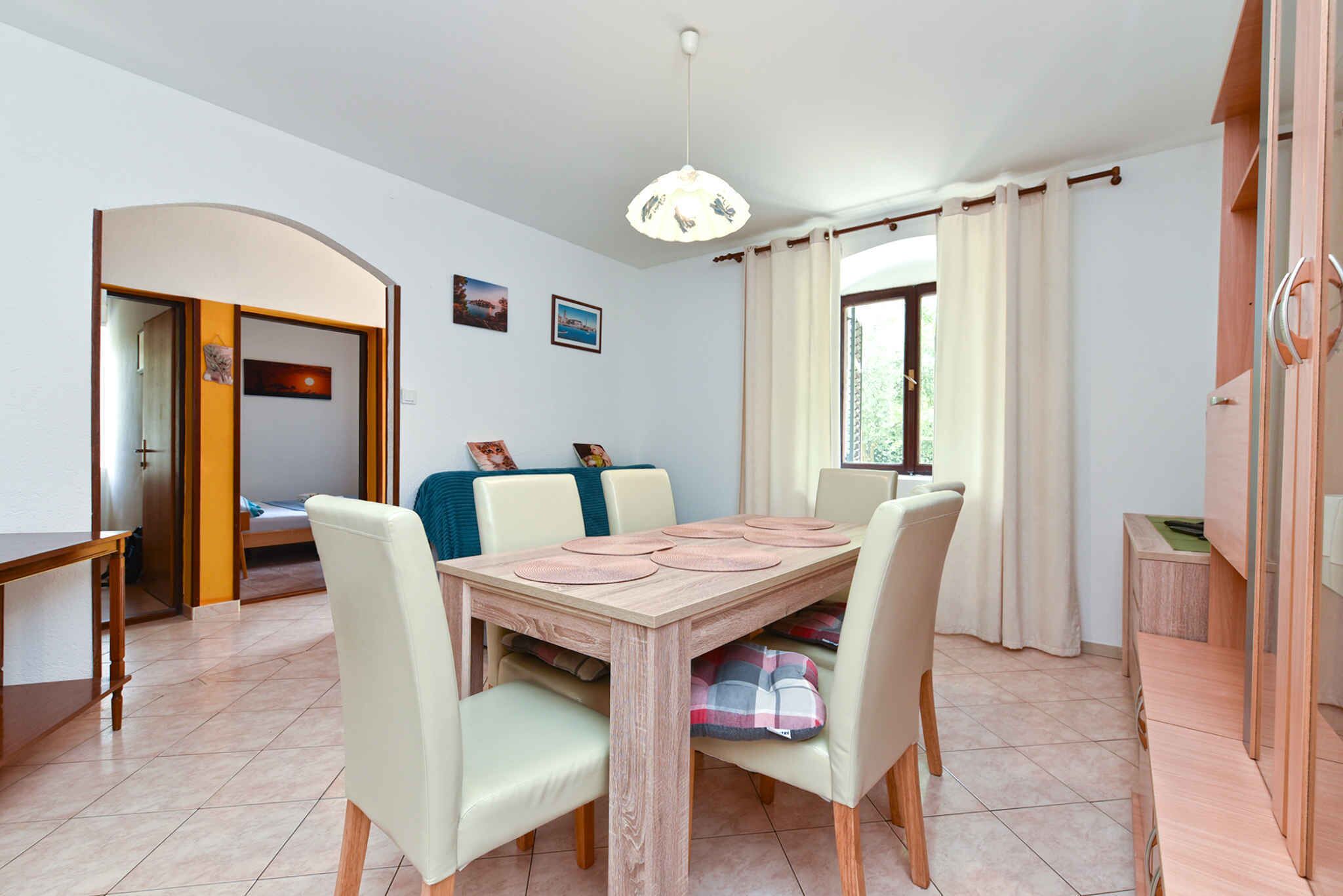 A dining area with a wooden table, four chairs, and a hanging light fixture.