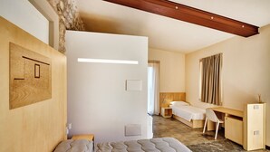 A modern hotel room with a large bed, a desk, and a small seating area.