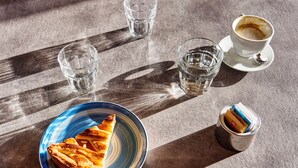 A table with a slice of pie, a cup of coffee, and a glass of water.