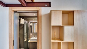 A modern bathroom with a glass shower, a sink, and wooden shelving.