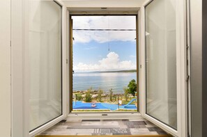 A room with a view of a beach and sea through a glass door.