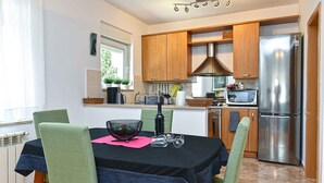 A modern kitchen with wooden cabinets, a stainless steel refrigerator, a microwave, and a dining table set for four. - Holiday apartment with air conditioning (Pula)