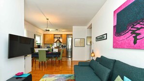 A modern living room with a teal sofa, a flat-screen TV, and a colorful rug. - Holiday apartment with air conditioning (Pula)