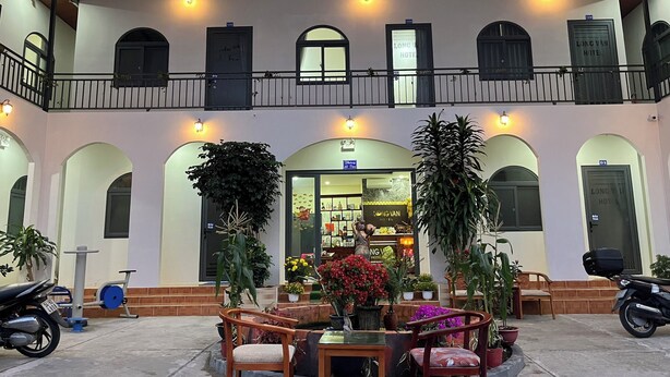 A hotel courtyard with a seating area, potted plants, and a visible shop. - Long Vân Hotel (Phu Quoc)
