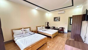 A hotel room with two wooden beds, a small table, a chair, a TV, and an air conditioning unit. - Long Vân Hotel (Phu Quoc)