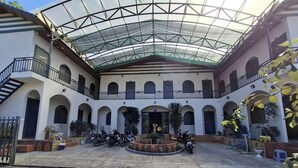 A spacious courtyard with a glass roof, surrounded by white buildings with arched windows and balconies. - Long Vân Hotel (Phu Quoc)
