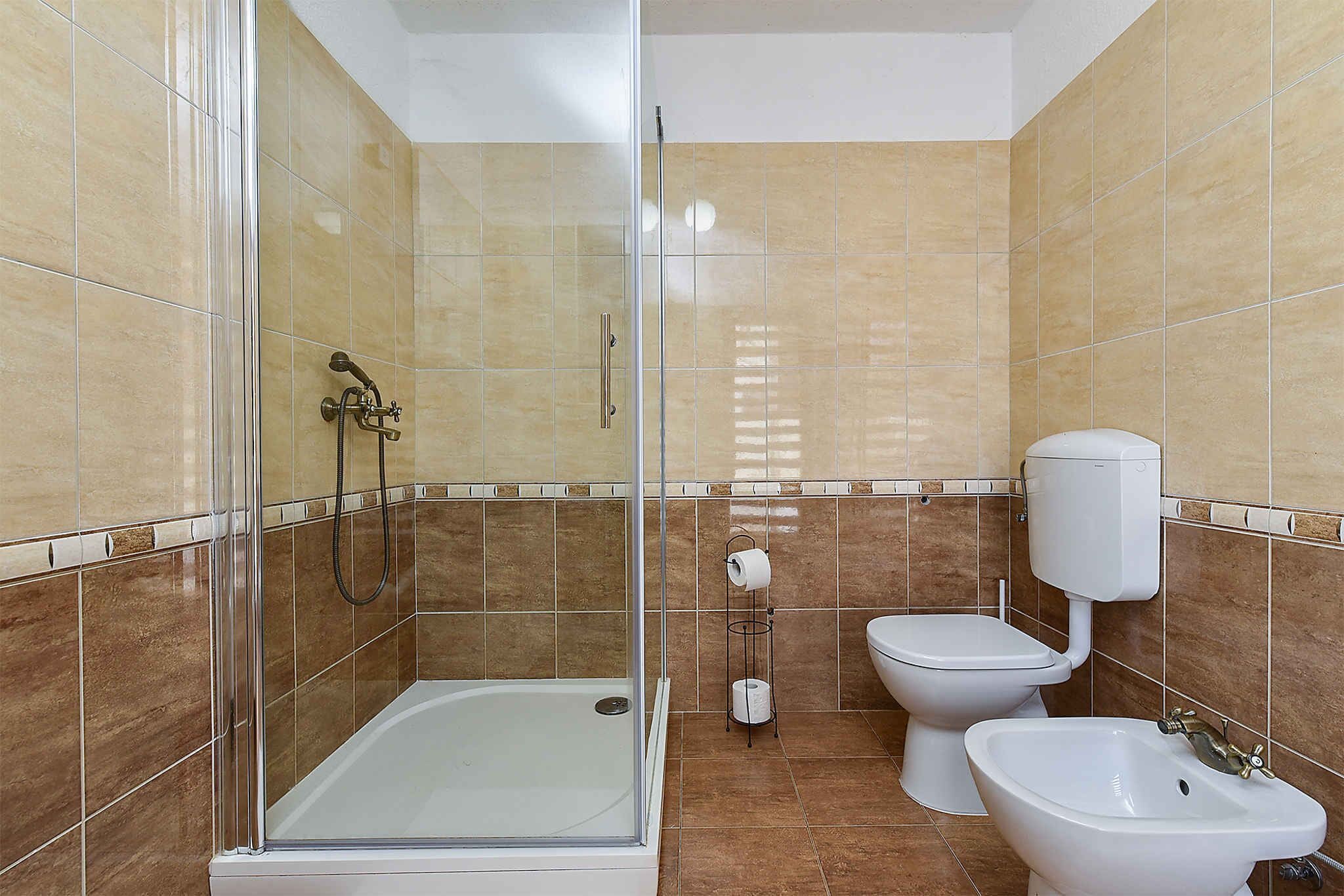 A bathroom with a glass-enclosed shower, a toilet, and a bidet.