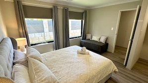 A hotel room with a large bed, a sofa, and a window with curtains.