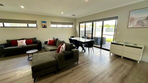 A spacious living area with a sofa set, a dining table, and a white cabinet.