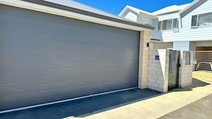 A modern residential building with a closed garage door, a gated entrance, and a clear sky.