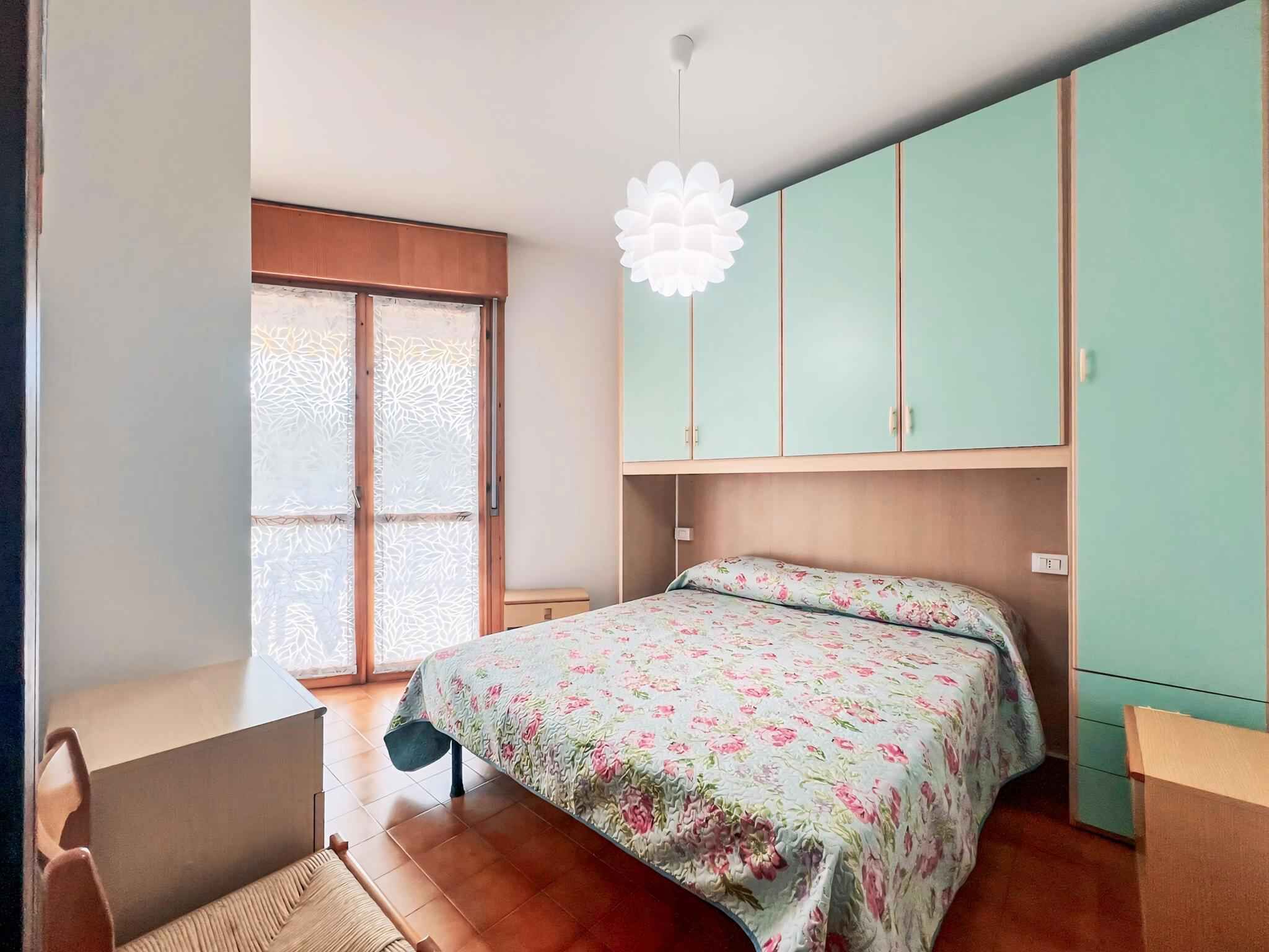 Ein Schlafzimmer mit einem Bett, einem Schreibtisch und einem Fenster mit satiniertem Glas.