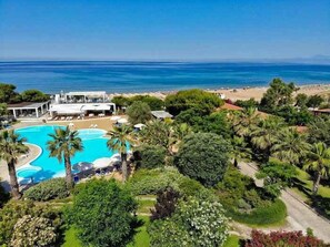 Un complexe hôtelier doté d’une piscine, d’une végétation luxuriante et offrant une vue sur l’océan.