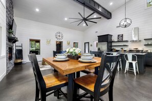 A modern kitchen with a central island, a dining area with a wooden table and chairs, and a fireplace.