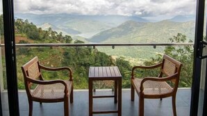 A balcony with two wicker chairs and a small table, overlooking a mountainous landscape with a clear sky. - Nuga Retreat (Illagolla)
