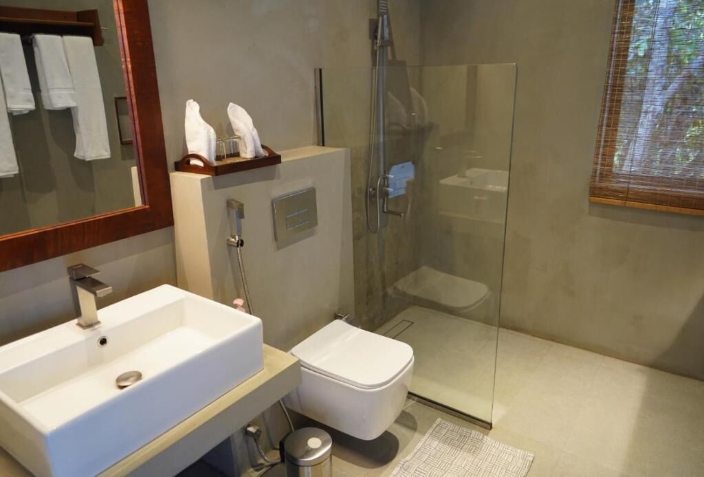 A modern bathroom with a white sink, toilet, and glass shower enclosure.