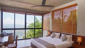 A bedroom with a large bed, a desk, and a chair, with a view of the outdoors. - Nuga Retreat (Illagolla)