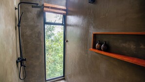 A bathroom with a shower, a window, and a shelf with decorative items. - Nuga Retreat (Illagolla)